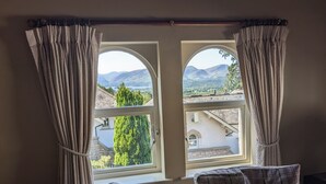 A room with two windows offering a view of a mountainous landscape. There are two plaid-patterned chairs in the room. - Spacious house, high in the hills, stunning views, on-site indoor pool, bar, gym (Keswick)