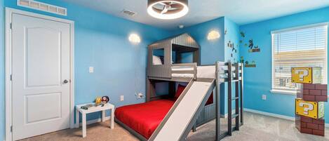 A child's bedroom with bunk beds, a slide, and a window with blinds.