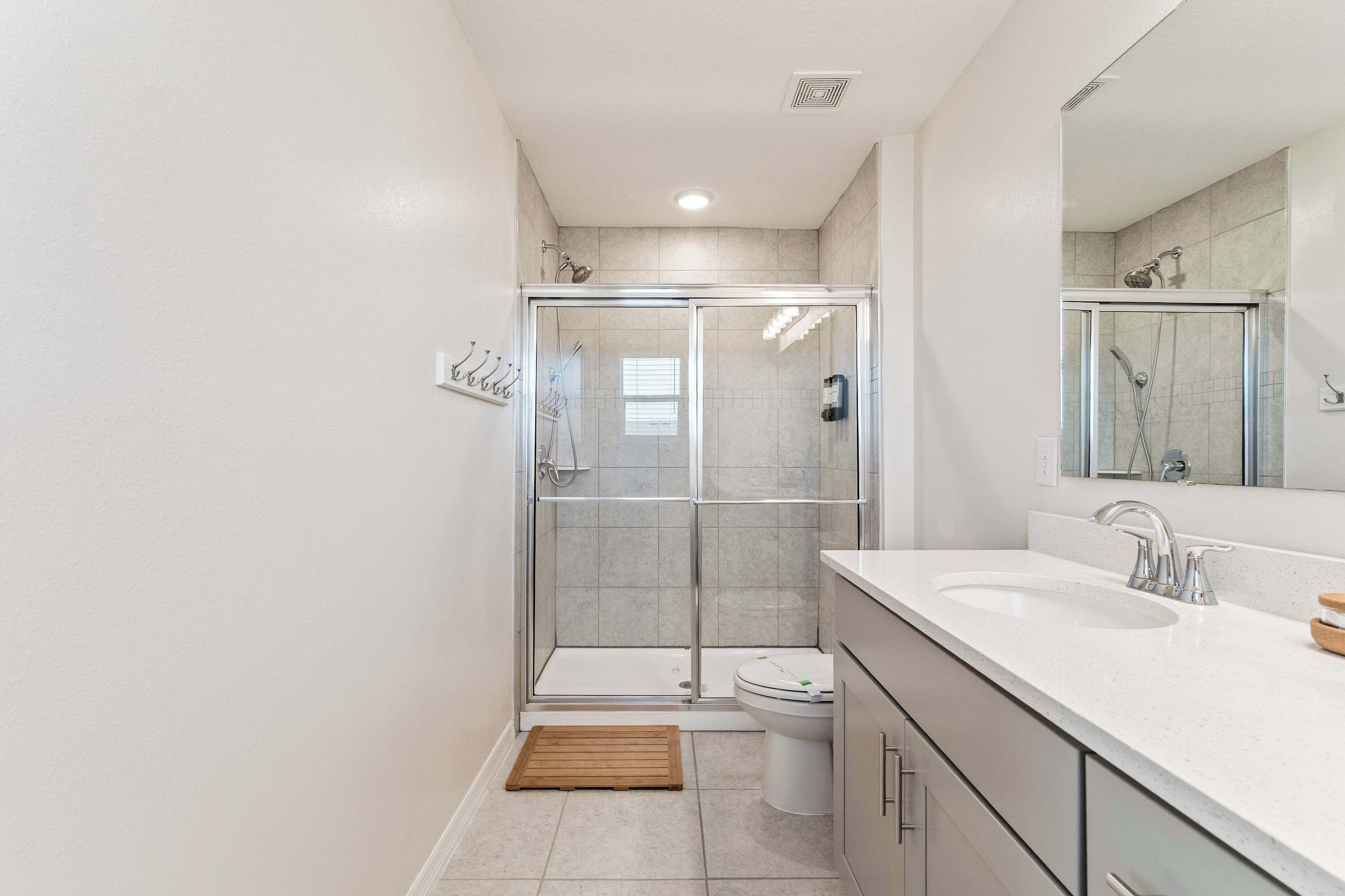 A modern bathroom with a glass-enclosed shower, a white sink, and a toilet.
