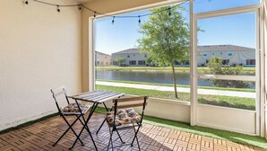 Ein Balkon mit Tisch und Stühlen, Blick auf ein Gebäude über dem Wasser, und eine Lichterkette.