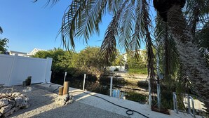 A residential outdoor area with a gravel patio, a white fence, and a palm tree. - 3/2 waterfront home w/54ft dock with WiFi, AC in wonderful Summerland Key (Summerland Key)