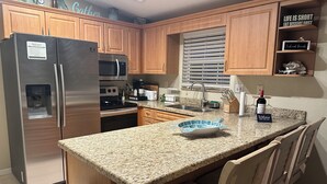 A kitchen with wooden cabinets, stainless steel appliances, a granite countertop, and a bar area with a bottle of wine. - 3/2 waterfront home w/54ft dock with WiFi, AC in wonderful Summerland Key (Summerland Key)