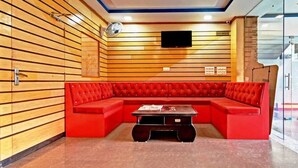 Ein modernes Interieur mit einem roten Modulsofa, einem kleinen Tisch und einem an der Wand befestigten Flachbildfernseher.