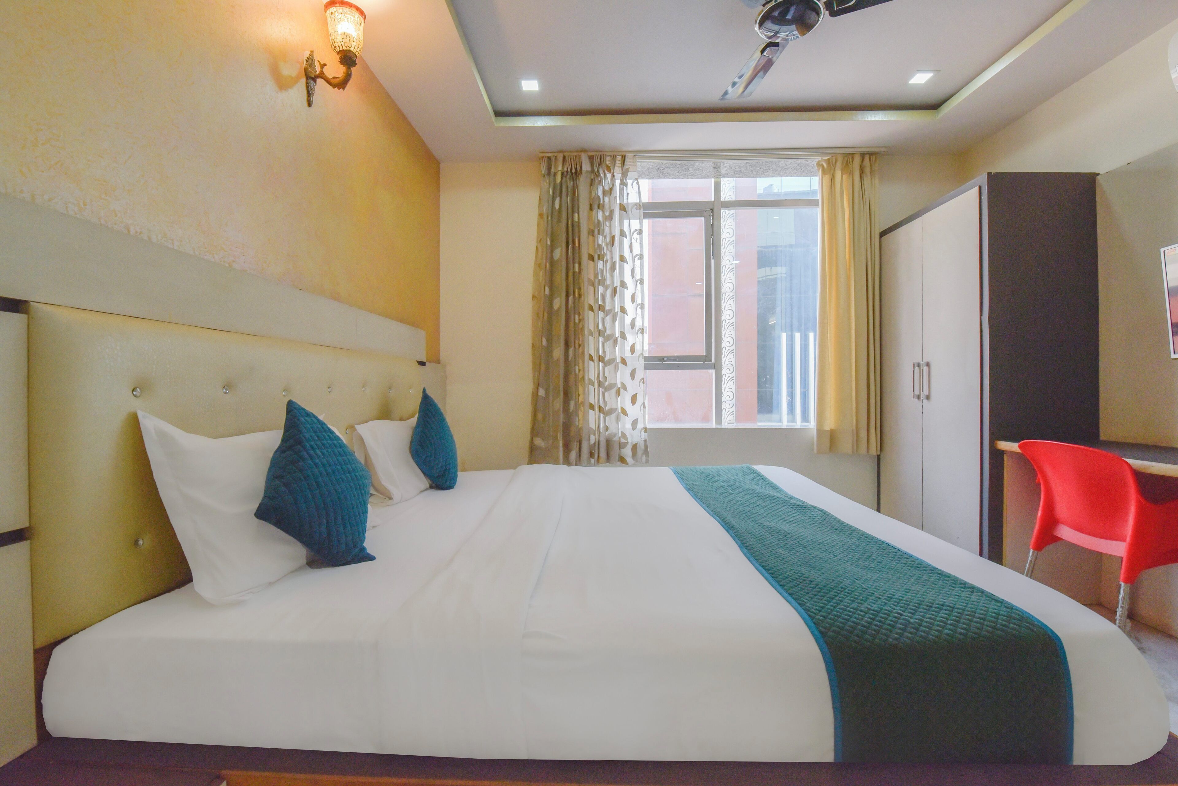 A hotel room with a large bed, a desk, and a wardrobe.