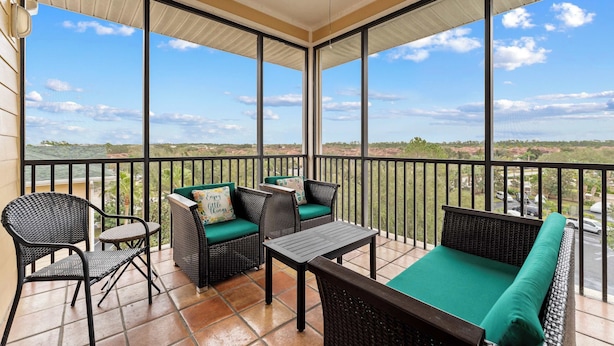 A balcony with wicker furniture, a green cushioned sofa, and a small table.