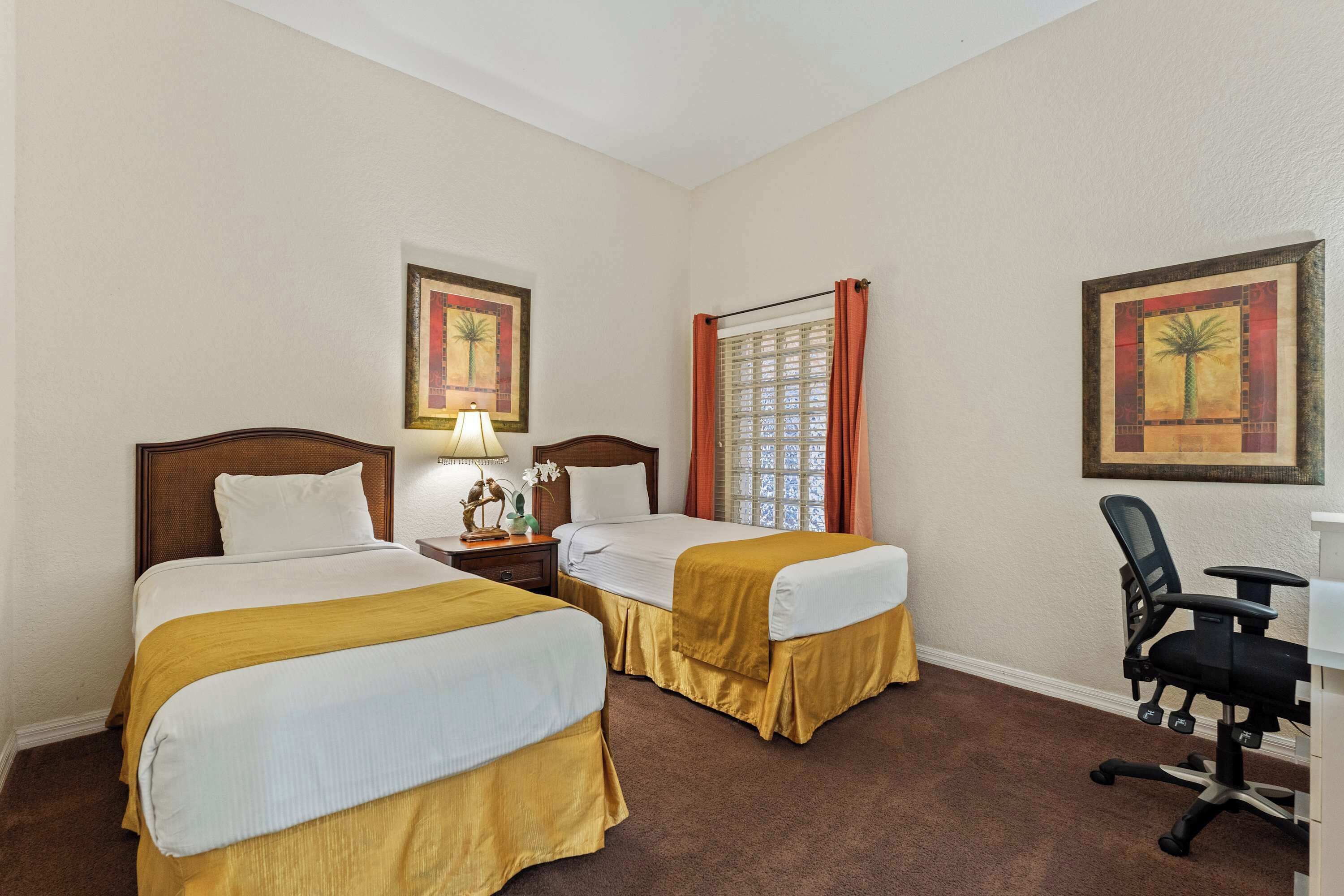 Ein Hotelzimmer mit zwei Betten, einem Schreibtisch und einem Sessel.