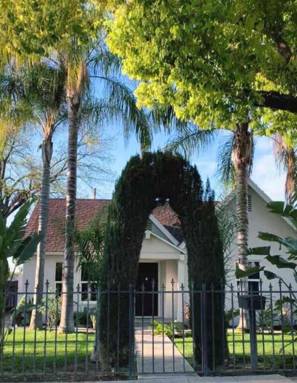 Traditional home with a, serene atmosphere, surrounded by a well-maintained lawn and a metal fence.