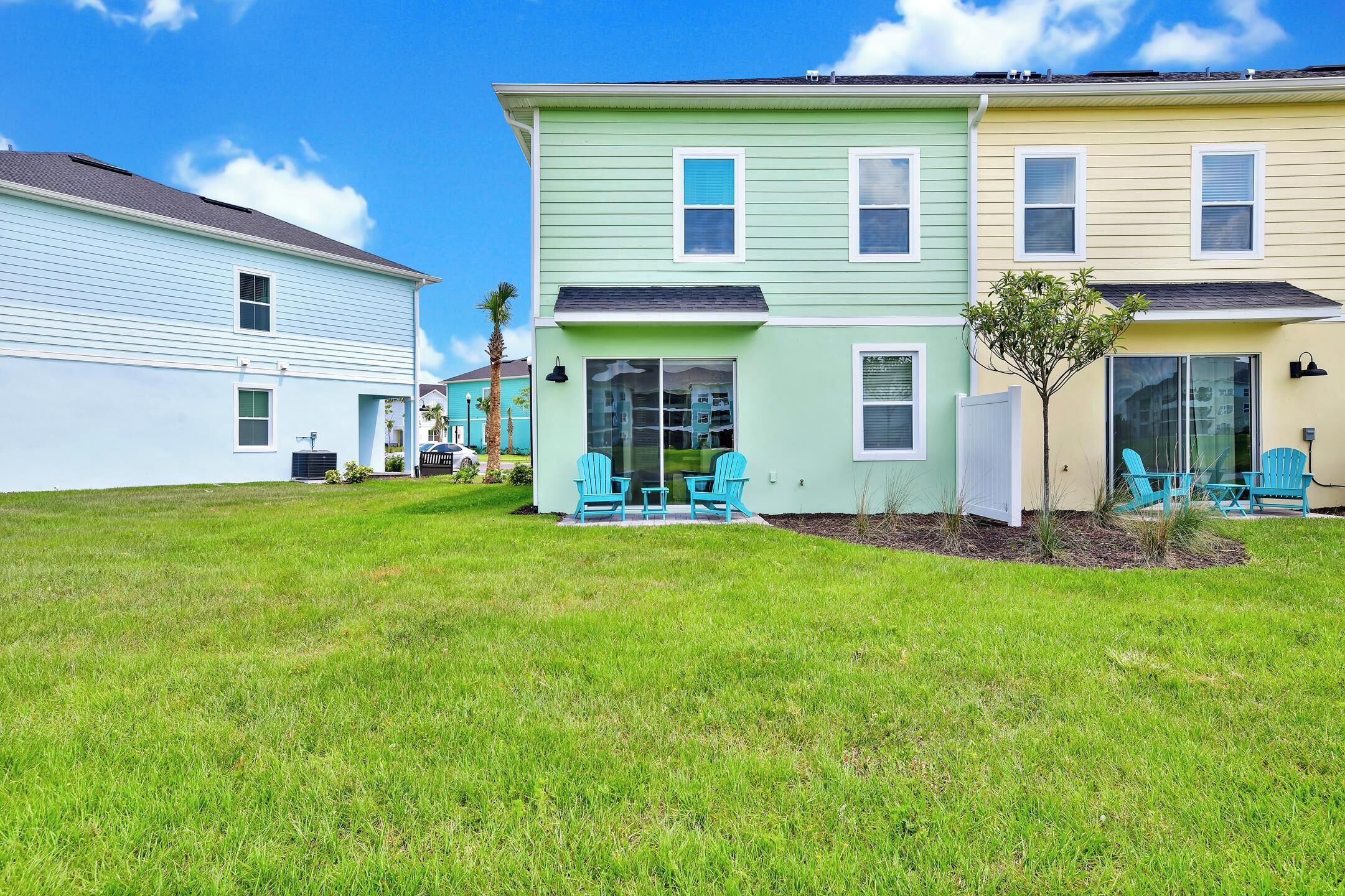 A row of colorful townhouses with a grassy yard and outdoor seating area.