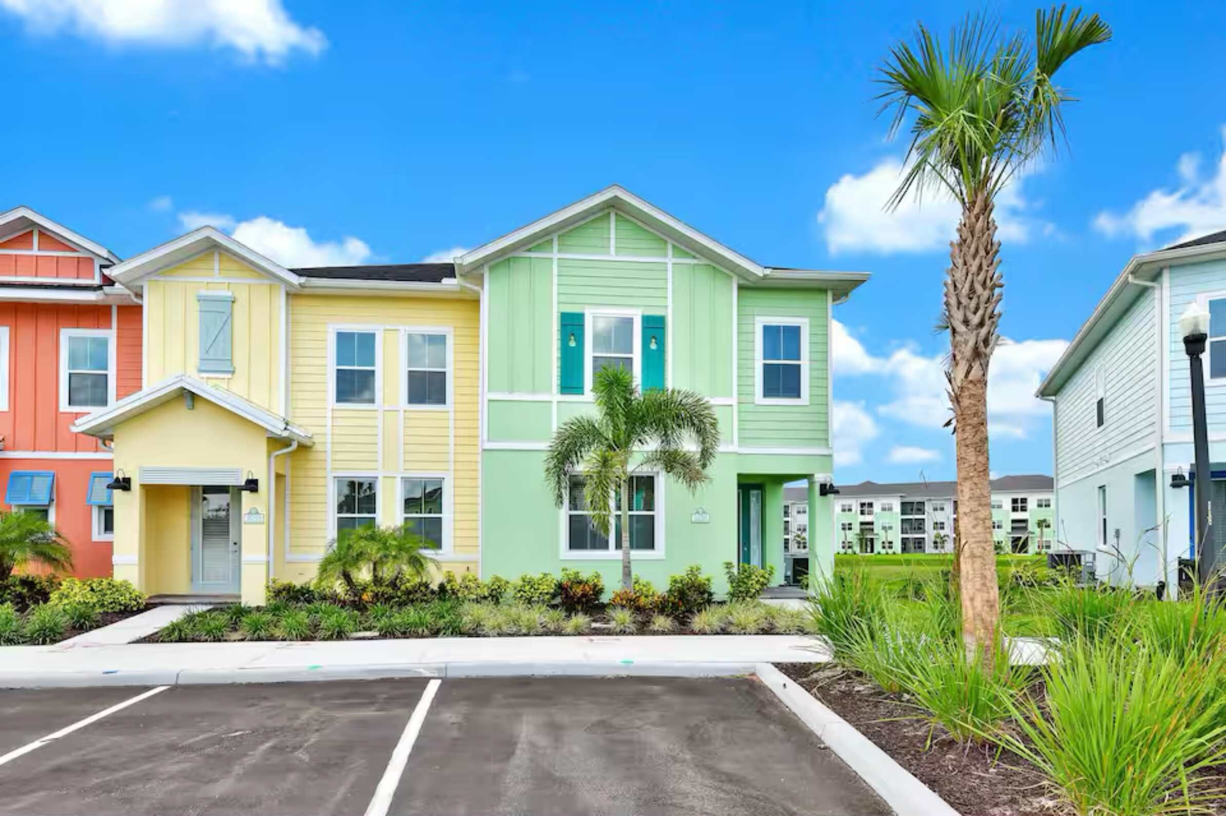 A row of colorful townhouses with a parking lot in front.