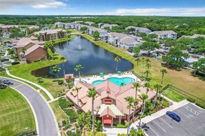 A residential area with a large swimming pool surrounded by houses and palm trees. - Playing Hooky (Kissimmee)