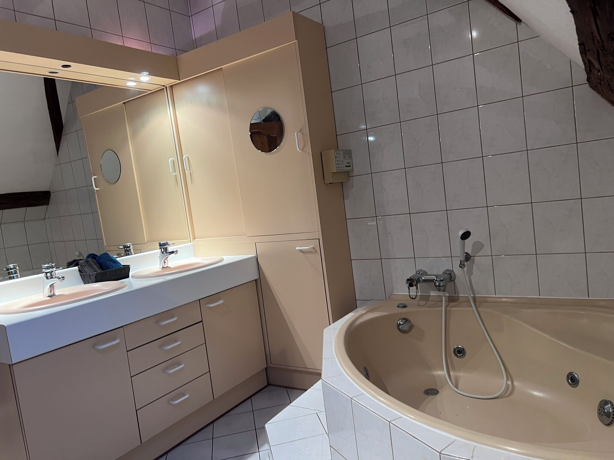 Ein modernes Badezimmer mit einem Doppelwaschtisch, einer großzügigen freistehenden Badewanne und einem Spiegel mit rundem Spiegel darüber.