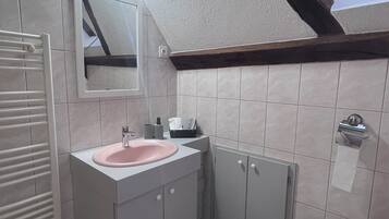 A bathroom with a white sink, mirror, and toilet. There is a towel rack and a small window above the toilet.