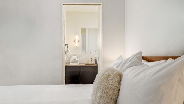 Une chambre à coucher avec un lit, un oreiller moelleux et une table de chevet sur laquelle sont posés des articles de toilette.