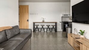Une cuisine moderne avec un îlot central, des tabourets de bar et un grand téléviseur.