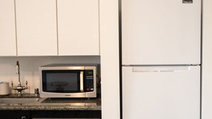 A compact kitchen with a microwave and a white refrigerator. - Salted Roots Basecamp: 1 Bedroom Flat Downtown (Anchorage)