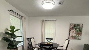 A dining area with a round table and chairs, a potted plant, and a ceiling light fixture. - Charming 2-bedroom house with WiFi, AC in fantastic Downtown Lake City (Lake City)