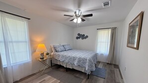 A bedroom with a bed, a ceiling fan, a nightstand with a lamp, and a wall-mounted clock. - Charming 2-bedroom house with WiFi, AC in fantastic Downtown Lake City (Lake City)