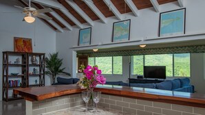 A kitchen with a marble countertop, a wooden island, and a view of the outdoors through large windows. - Caribbean Escape - Sunset Palms! (Christiansted)