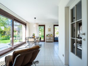 A spacious room with large windows, a dining area with a table and chairs, and a cozy seating area with a sofa.