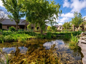 A serene pond with clear water, surrounded by lush greenery and traditional buildings with tiled roofs. - Villa Zeebries by Interhome (Bredene)