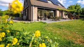 Une maison moderne dotée d’un toit en pente, de panneaux solaires et d’un patio couvert.