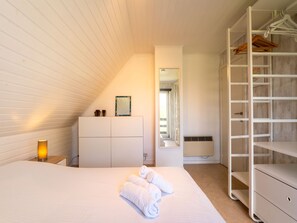 A bedroom with a bed, a dresser, a walk-in closet, and a mirror.
