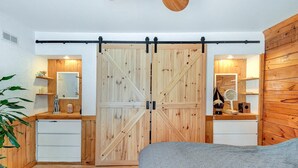 Un dormitorio con un amplio ventanal corredera, suelo de madera, cama y ventilador de techo.