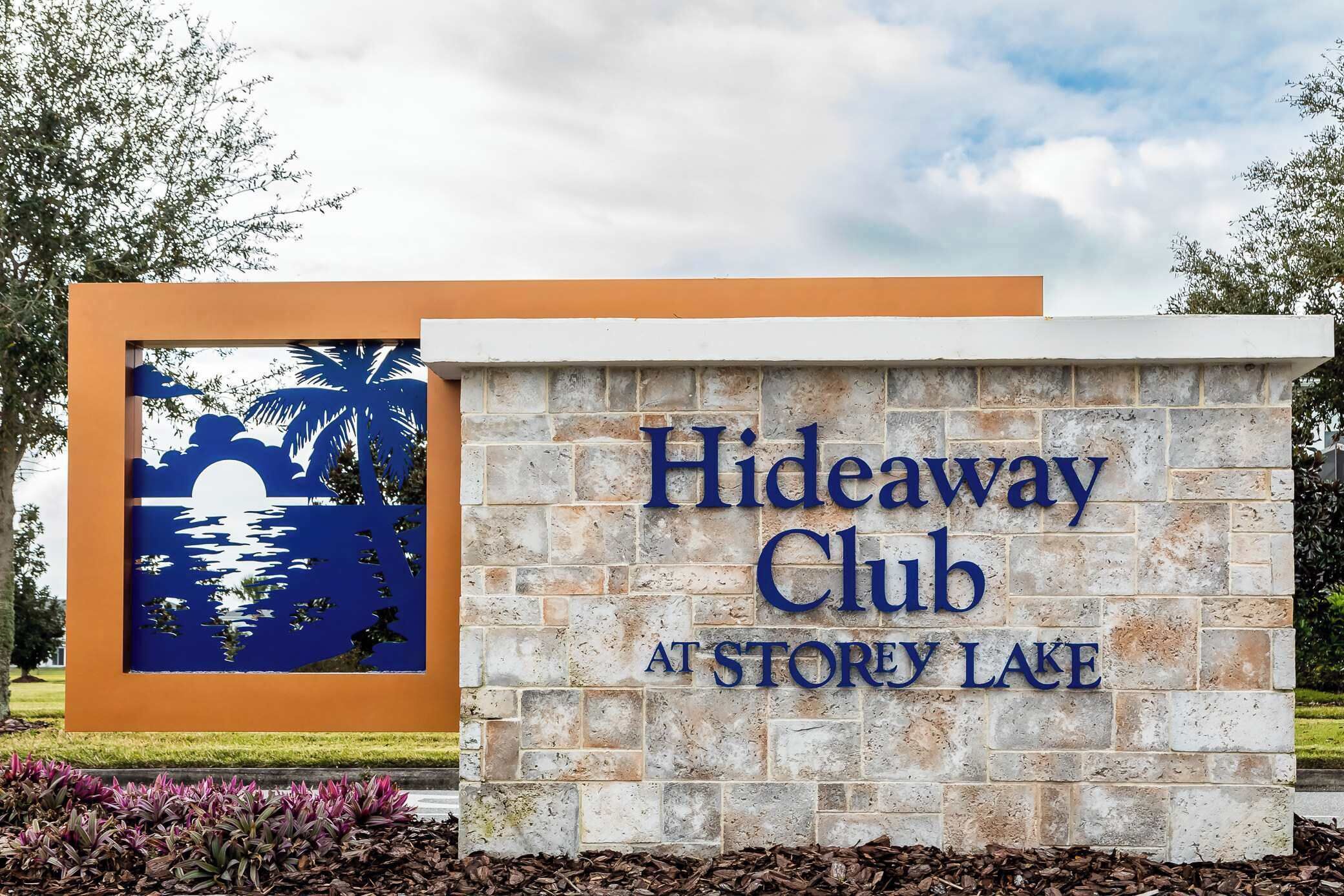 A sign for Hideaway Club at Storey Lake with a sunset mural.