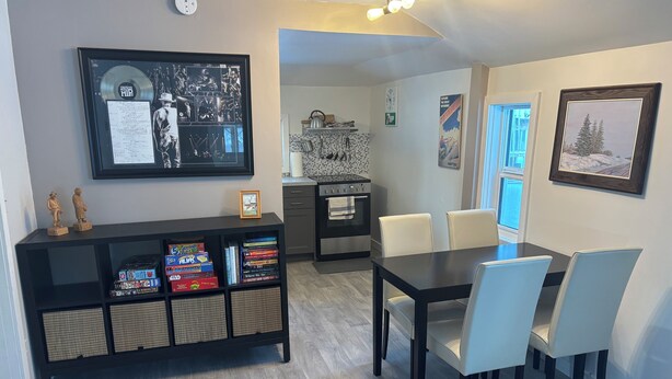 Una cucina moderna con zona pranzo, caratterizzata da un tavolo consolle nero, sedie bianche e un quadro appeso al muro.