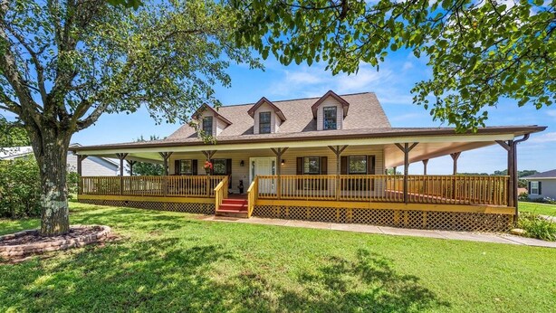 A two-story house with a covered porch and a staircase leading to the entrance. - Spacious Home •Pet Friendly •Mtn Views & Firepit! (Sevierville)