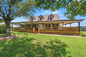 A two-story house with a covered porch and a staircase leading to the entrance. - Spacious Home •Pet Friendly •Mtn Views & Firepit! (Sevierville)