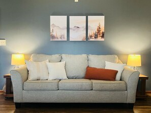 A living room with a sofa, two lamps, and three framed pictures on the wall. - Spacious Home •Pet Friendly •Mtn Views & Firepit! (Sevierville)