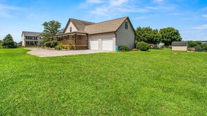 A single-story house with a front porch, a garage, and a well-maintained lawn. - Spacious Home •Pet Friendly •Mtn Views & Firepit! (Sevierville)