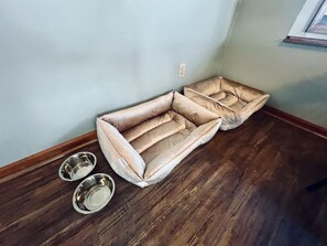 A room with a wooden floor, a beige cushioned bench, and two metal bowls. - Spacious Home •Pet Friendly •Mtn Views & Firepit! (Sevierville)
