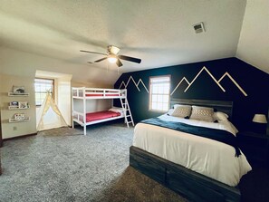 A bedroom with bunk beds, a ceiling fan, a window, and a bookshelf. - Spacious Home •Pet Friendly •Mtn Views & Firepit! (Sevierville)