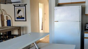 Une cuisine moderne avec un plan de travail blanc, un four encastré et un réfrigérateur.