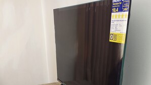 Un televisor sobre una mesa de madera con un control remoto a un lado.