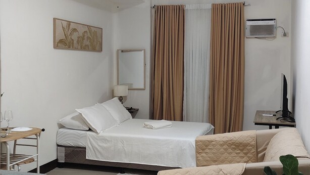 Una habitación de hotel con cama, sofá, escritorio y una planta en maceta.
