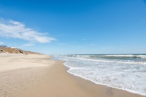 Ein Strand mit sandigem Ufer und blauem Himmel.