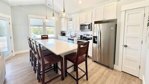 A modern kitchen with a large island, stainless steel appliances, and white cabinetry.