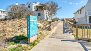 A wooden boardwalk leading to beach access with a sign detailing beach regulations and safety information. - Cast A Wave | Steps to Beach & Pool (Corolla)