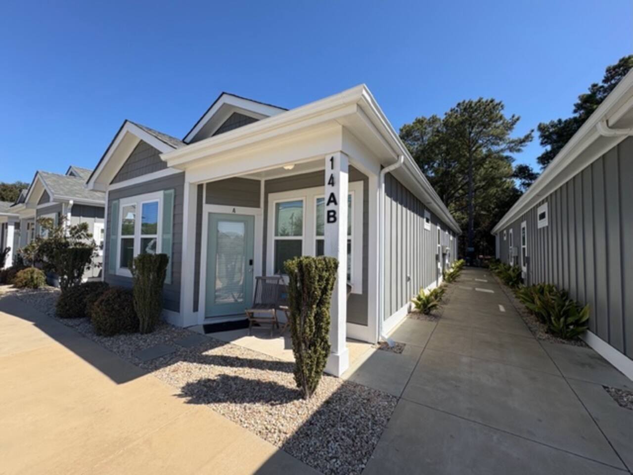 A modern residential building with a covered porch, a visible mailbox, and a clear sky.