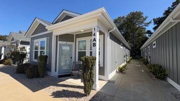 A modern residential building with a covered porch, a visible mailbox, and a clear sky.