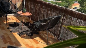 A balcony with wicker furniture, a small table, and a decorative wall.
