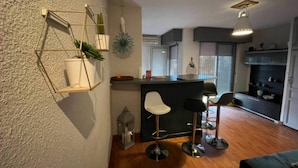 A modern kitchen with a central island, bar stools, and a hanging light fixture.