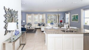 A modern kitchen with a granite countertop, white cabinetry, and a stainless steel sink. - Sun-soaked At Solterra (Davenport)