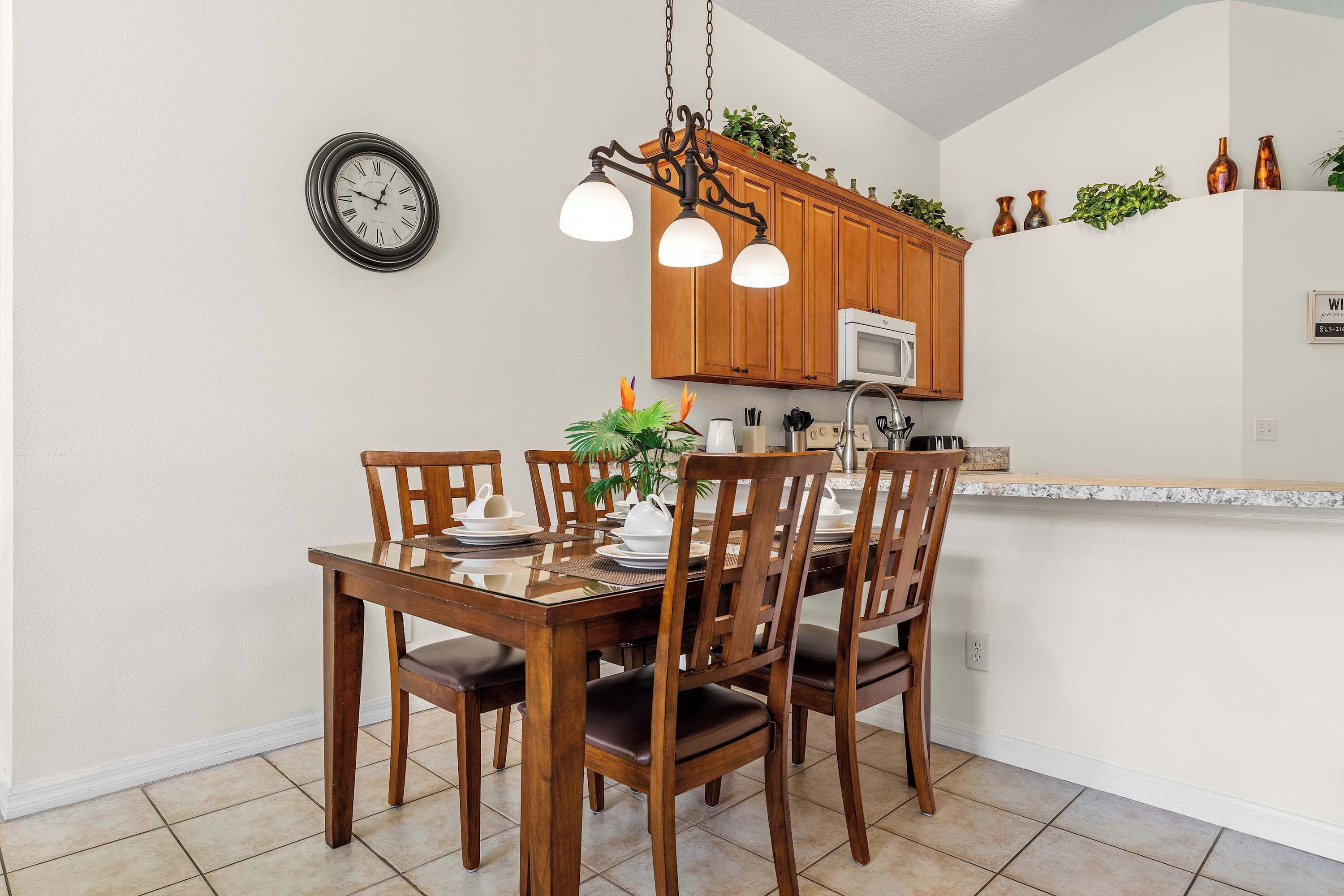 A dining area with a wooden table and chairs, a chandelier, and a clock on the wall.