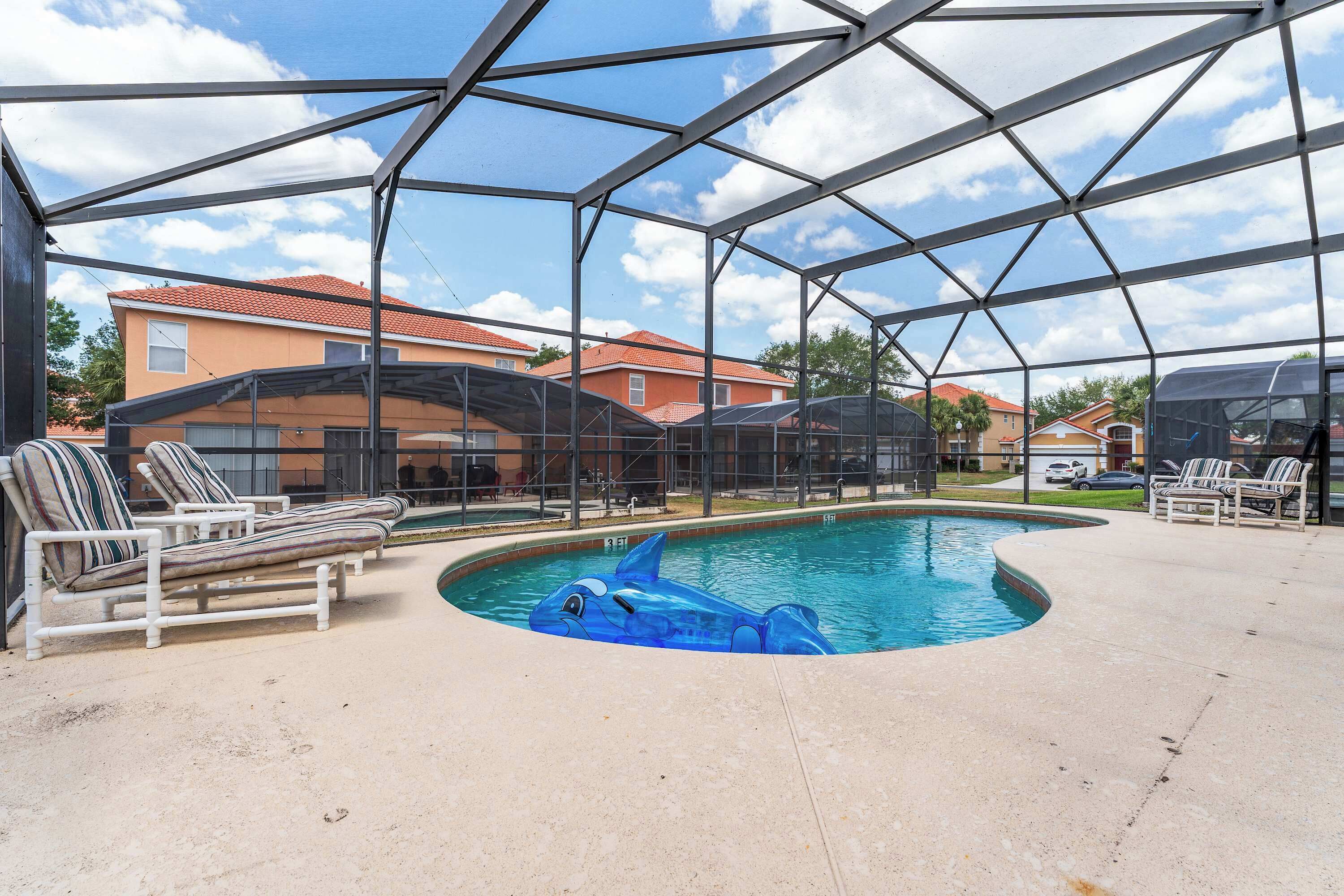 A covered swimming pool with lounge chairs and a dolphin floatation device.