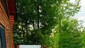 Een houten terras met een jacuzzi, twee ligstoelen en een kleine tafel.