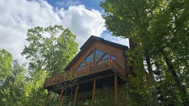 Een houten chalet met balkon, omringd door bomen.